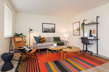 A living room with a striped rug and a grey couch.